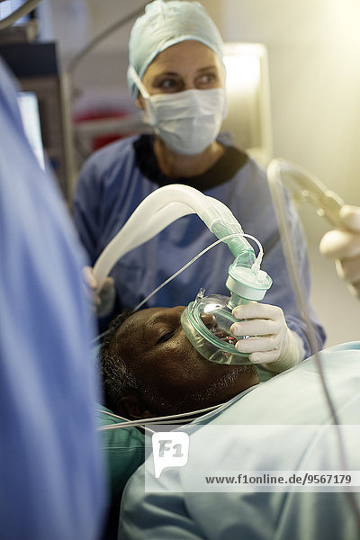 Anästhesist mit Sauerstoffmaske über dem Patienten während der Operation