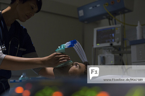 Arzt mit Sauerstoffmaske über dem Gesicht des Patienten auf der Intensivstation