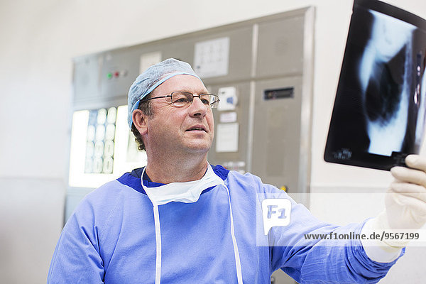 Arzt mit OP-Kappe und OP-Kittel beim Röntgen im Operationssaal