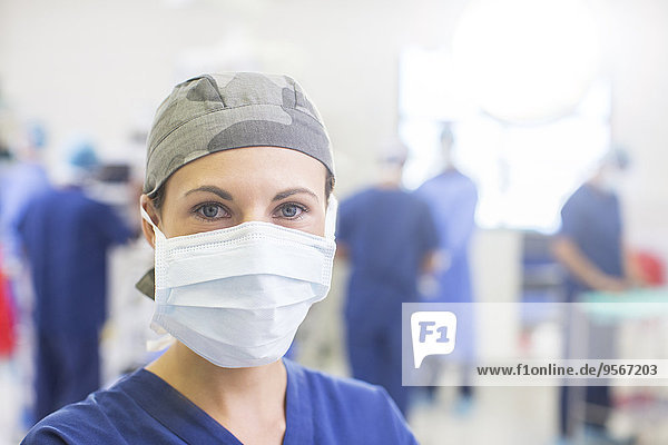 Portrait of female doctor wearing surgical cap and mask in operating theater