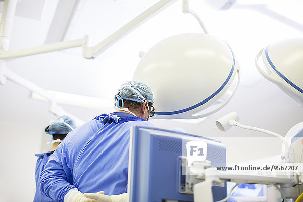 Rückansicht des Arztes mit OP-Kappe  Maske und Kittel im Operationssaal
