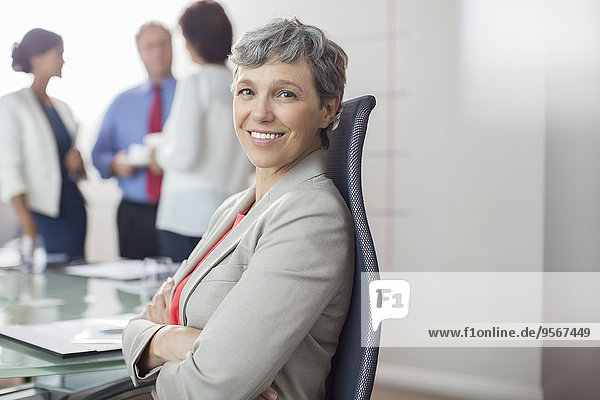 Portrait of businesswoman sitting in chair with arms crossed in conference room