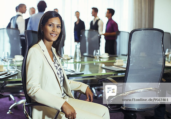 Businesswoman posing in conference room  colleagues standing background