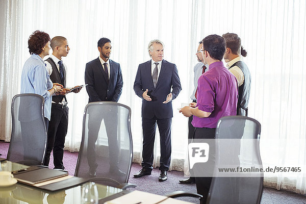 Group of business people standing by window discussing in conference room