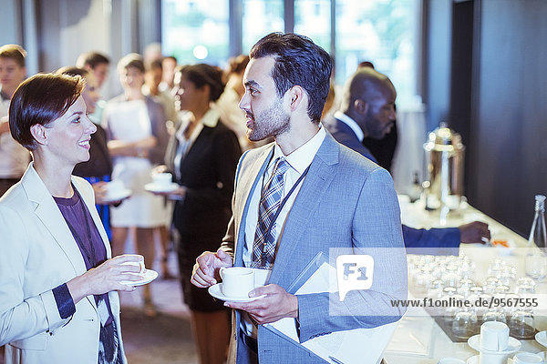 Portrait of man and woman talking in lobby of conference center during coffee break