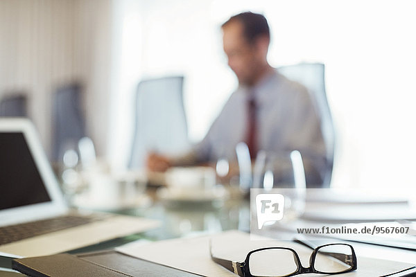Glasses on conference table  businessman sitting in background