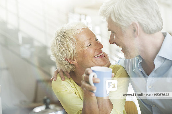 Ältere Paare umarmen sich mit Kaffeetasse