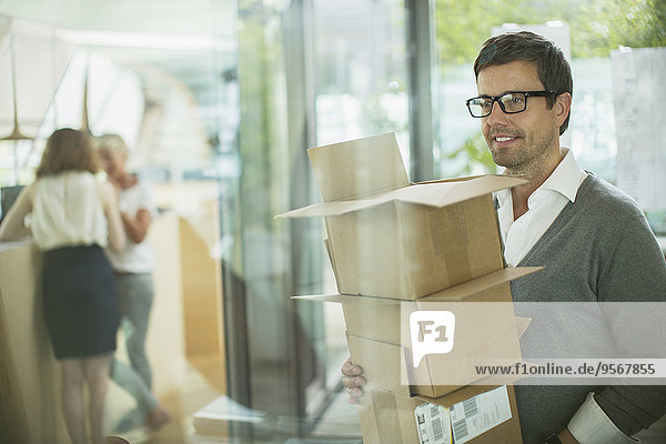 Businessman carrying cardboard boxes in office