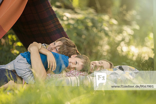 Father and sons relaxing together near camping tent