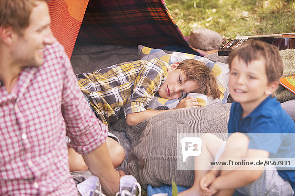 Vater und Söhne lächeln auf dem Campingzelt