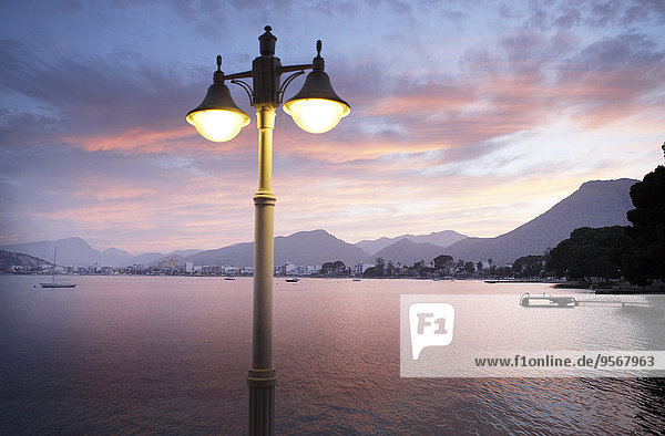 View of illuminated street light with bay and mountains in background