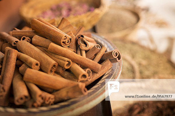 Cinnamon sticks on plate and other spices in background in spice market