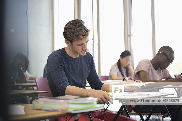 Universitätsstudent beim Examen  Studenten beim Schreiben im Hintergrund