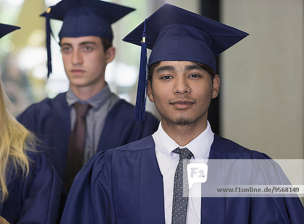 Männlicher Student in Abschluss-Kleidung mit Blick auf die Kamera