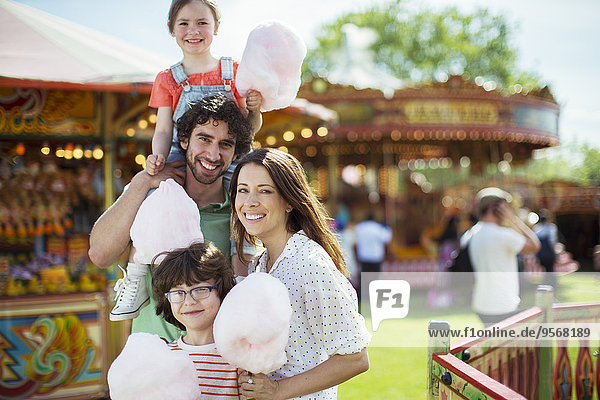 Porträt einer fröhlichen Familie mit rosa Zuckerwatte im Vergnügungspark