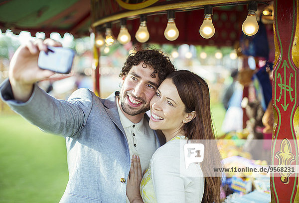 Lächelndes Paar nimmt Selfie im Vergnügungspark auf