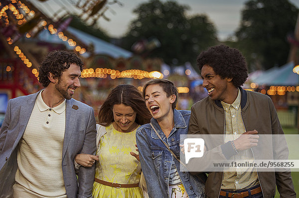 Two couples walking in amusement park and laughing at dusk