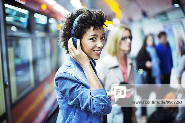 Lächelnde Frau hört Kopfhörer in der U-Bahn