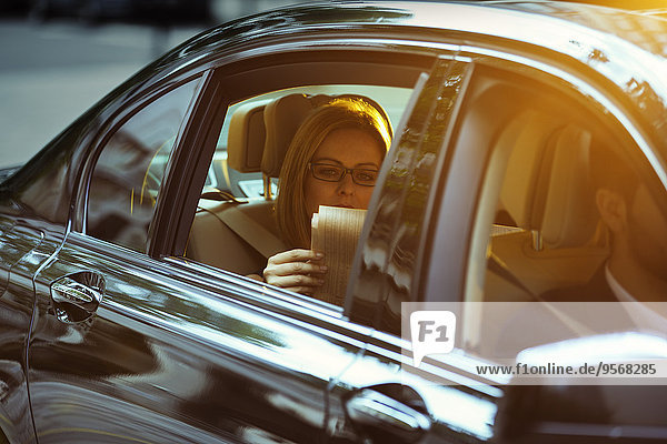 Geschäftsfrau liest Zeitung auf dem Rücksitz des Autos