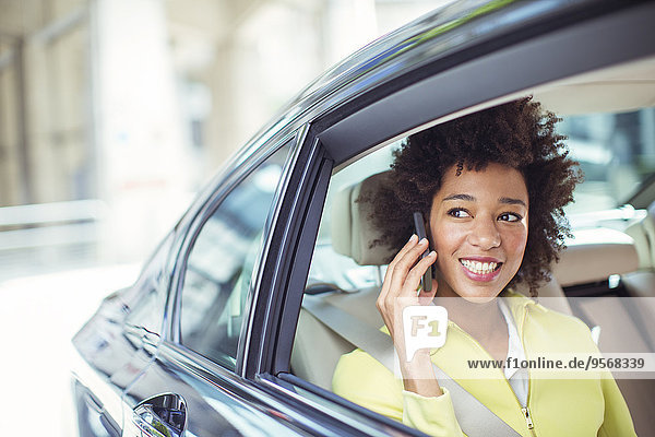 Geschäftsfrau beim Telefonieren auf dem Rücksitz des Autos