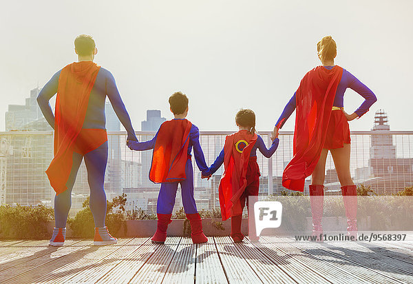 Superheldenfamilie steht auf dem Stadtdach