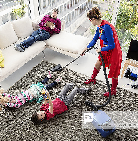 Superhelden saugen im Wohnzimmer um die Familie herum