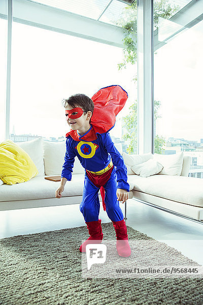 Superheldenjunge spielt im Wohnzimmer