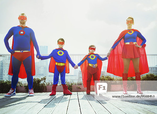Superheldenfamilie hält Hände auf dem Stadtdach