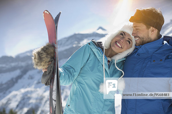 Couple with skis hugging at mountain