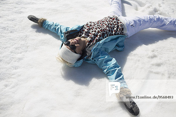 Happy woman making snow angels