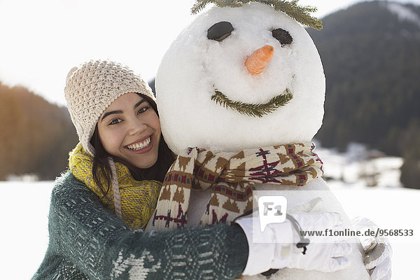 Portrait of smiling woman hugging snowman