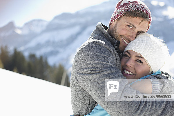 Portrait of smiling couple hugging in snow