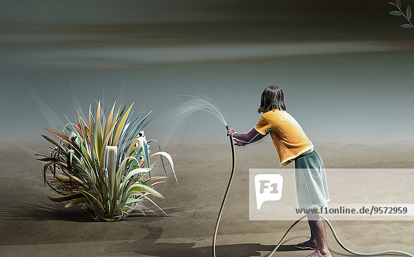 Teenagerin wässert eine Pflanze in der Wüste