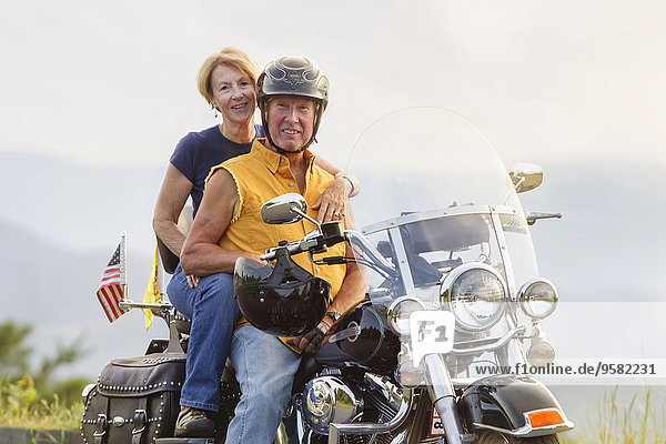 Older Caucasian couple smiling on motorcycle