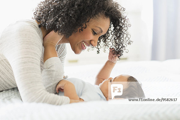 Mixed race mother holding baby on bed
