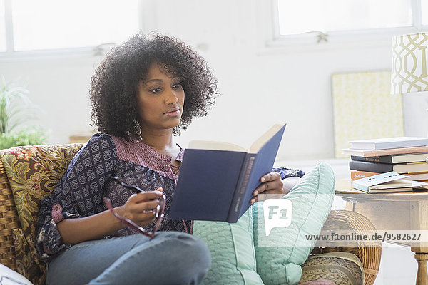 Mixed race woman reading book in living room