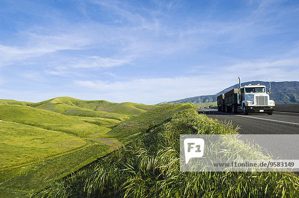 Truck driving on remote road in rolling landscape