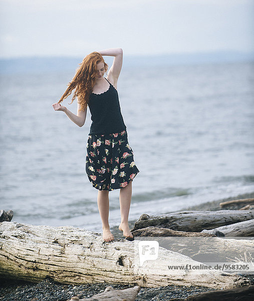 Girl walking on driftwood on beach