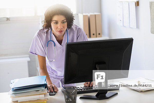 Mixed race nurse using computer in office