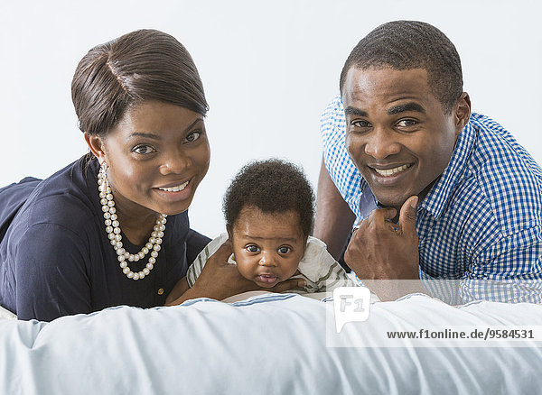 Couple smiling with baby son on bed