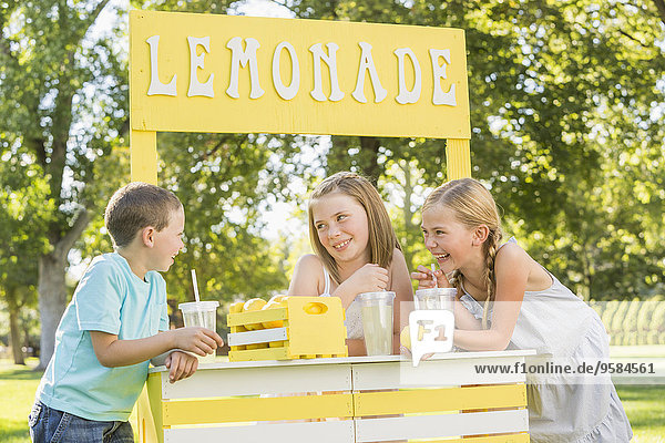 Caucasian children talking at lemonade stand