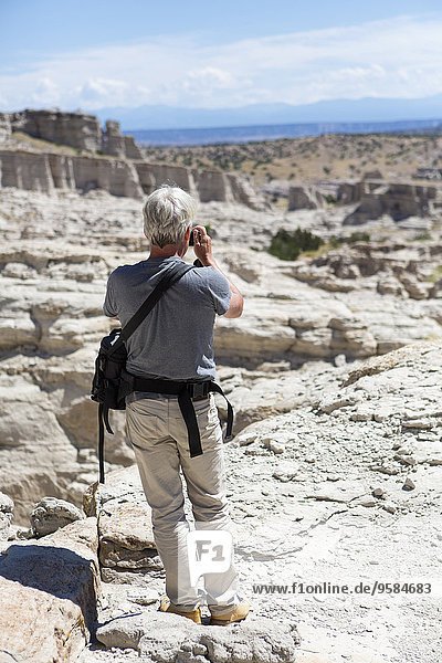 Older Caucasian man photographing rock formations  Abiquiu  New Mexico  United States