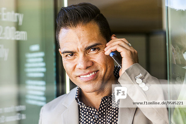Hispanic businessman talking on cell phone in doorway