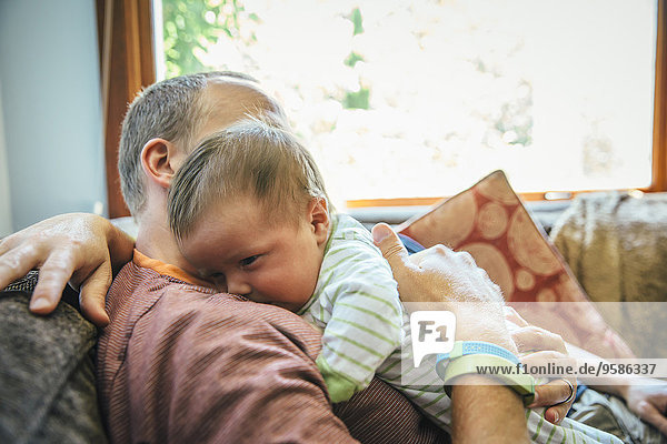 Caucasian father holding baby boy on sofa