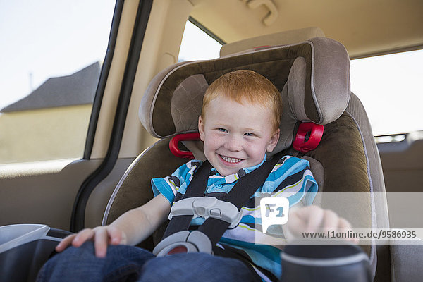 Caucasian boy smiling in car seat