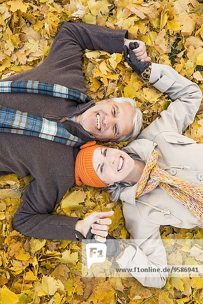 Older Caucasian couple smiling in autumn leaves