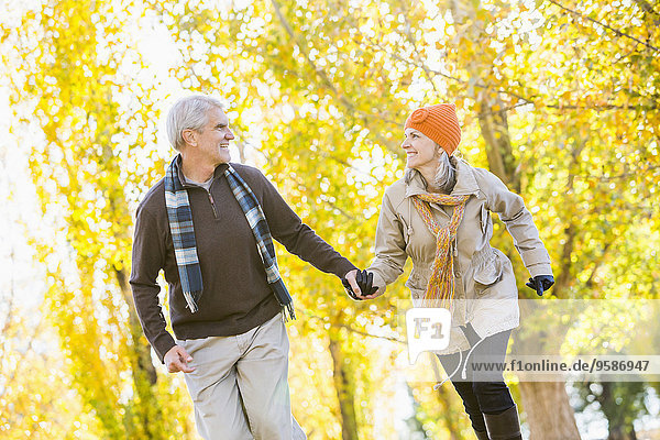 Older Caucasian couple walking near autumn trees