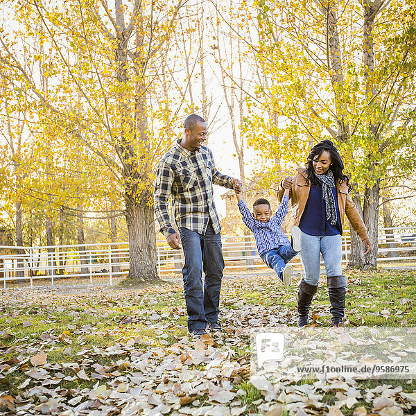 Black family playing in autumn leaves