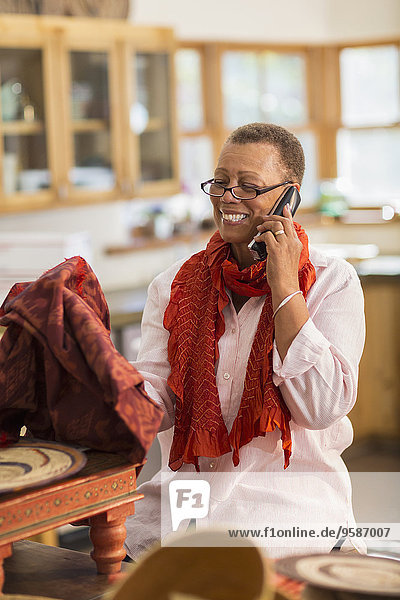 Older mixed race woman talking on telephone in home office