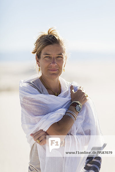 Caucasian woman wrapped in scarf on sand dune